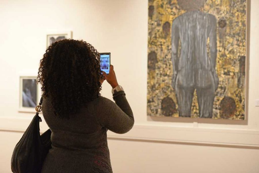 A reception guest takes a photo of one of the pieces of art in “Exposure: Black Voices in the Arts.” Meghan Sunners | Senior Staff Photographer