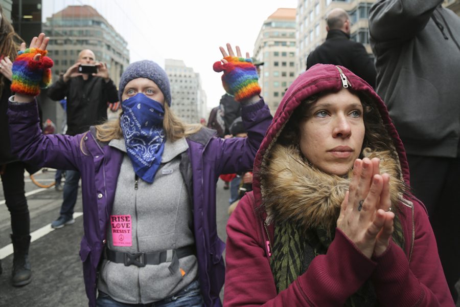 Protesters look towards a line of police in riot gear. Theo Schwartz | Senior Staff Photographer