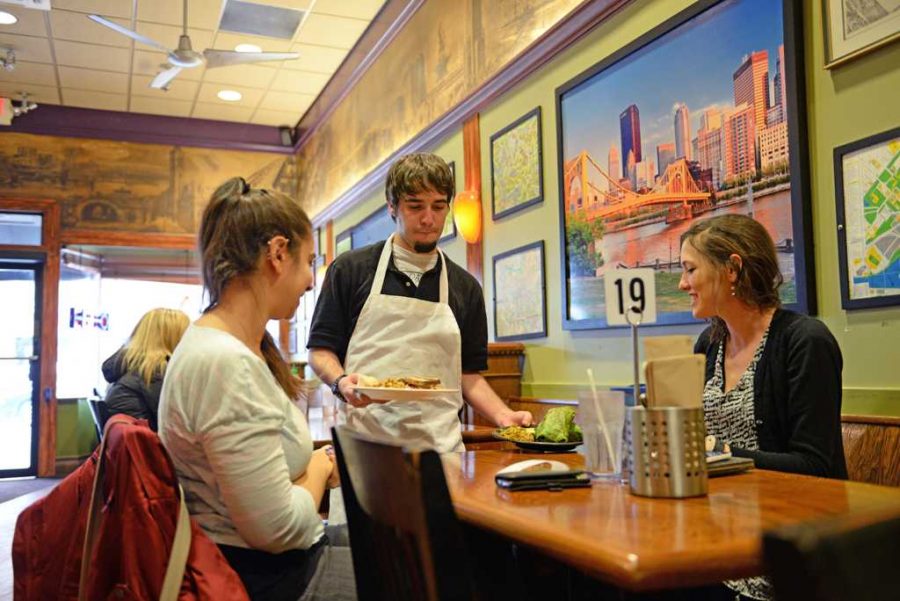 Aaron Kutchner, a server at Red Oak Cafe, serves vegetarian dishes to Kelly Williams (left), a Ph.D student in Public Health, and Adelina Malito (right), a Social Work Masters student.  Nikki Moriello  | Visual Editor 