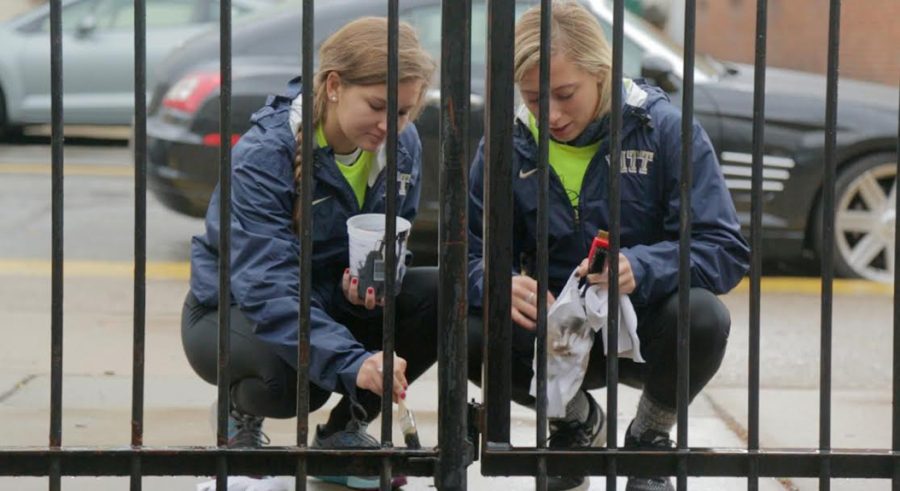Two Pitt students paint a fence outside Phillips Elementary School in the South Side on Pitt Make a Difference Day, Oct 22, 2016. Theo Schwarz | Senior Staff Photographer