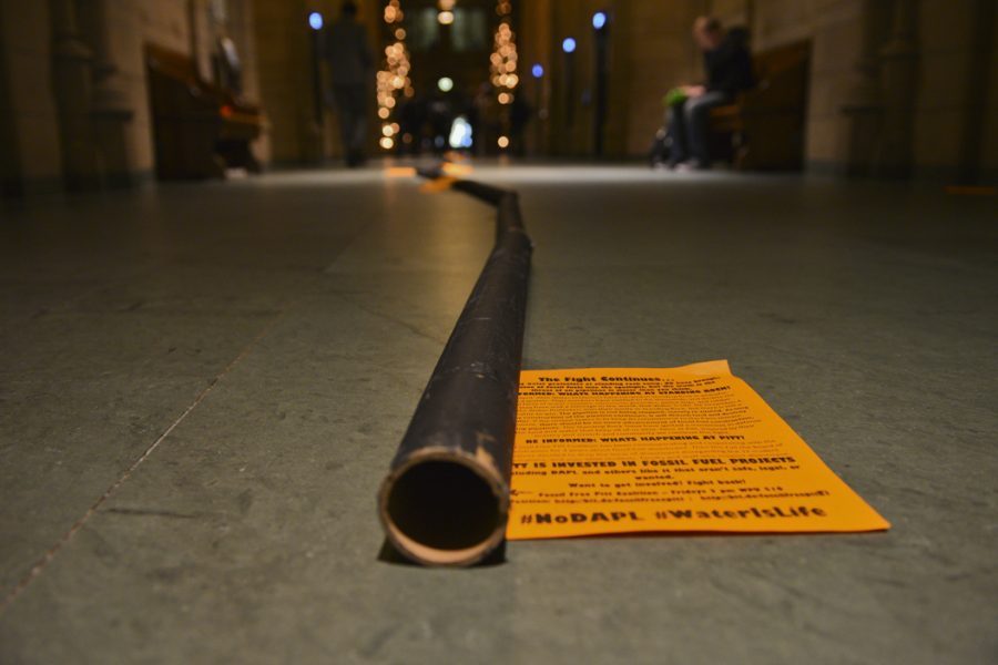 Members of the Fossil Free Pitt Coalition set up a cardboard “pipeline” in the Cathedral Monday. Stephen Caruso | Senior Staff Photographer