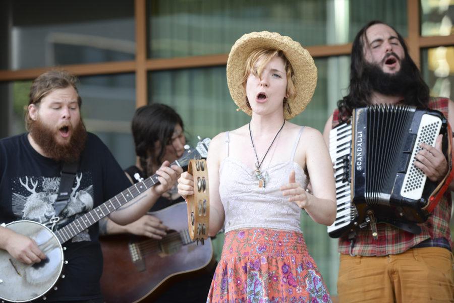 Several members of 4th River Music Collective, a street folk group, perform in front of the Wyndham Hotel at the Three Rivers Arts Festival on Saturday. (Photo by Anna Bongardino | Visual Editor)