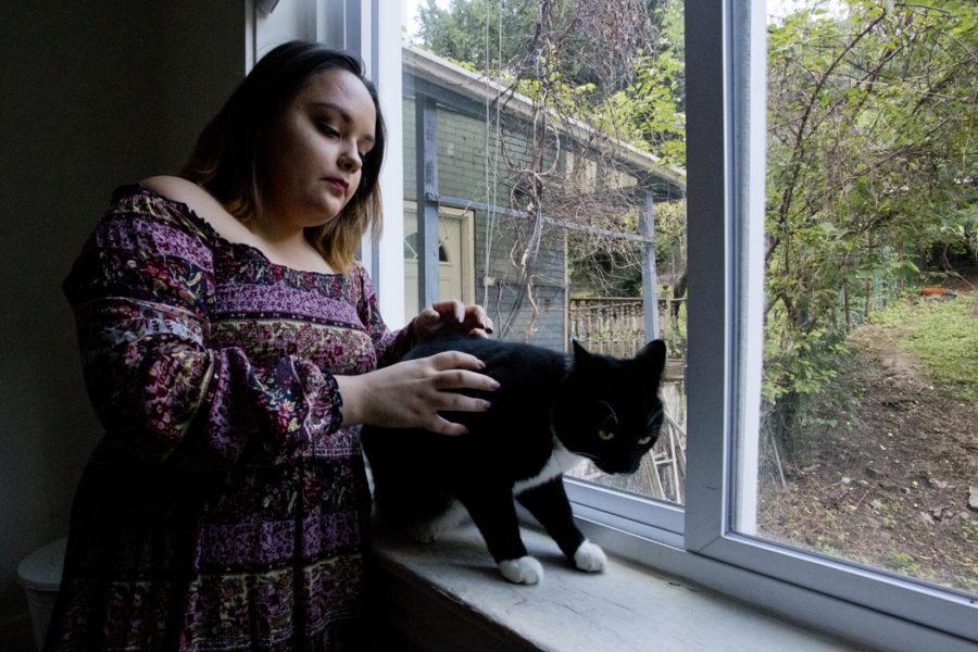 Fifth-year Pitt student Georgia Vidal pets her cat, Winston, on the windowsill of her Bates Street house. (Photo by Jordan Mondell | Contributing Editor)