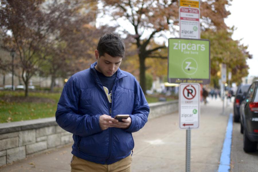 Ian Snyder, a senior political science major, logs into his Zipcar app at the Zipcar spot in front of the William Pitt Union on Forbes Avenue. (Photo by Wenhao Wu | Assistant Visual Editor)