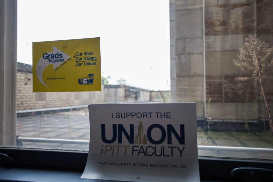 Signs supporting the grad and faculty unions hang on a window in the Cathedral of Leaning. (Photo by John Hamilton / Managing Editor)
