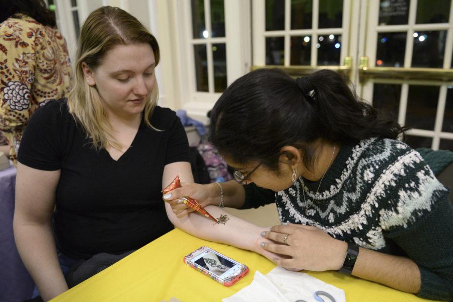 Lauren Kubeja (left), a junior studying civil engineering, receives a henna tattoo from Insiyah Campwala (right), a senior majoring in biology, at the Indian table during the Who Run the World? event Monday night in the William Pitt Union. (Photo by Issi Glatts | Staff Photographer) 