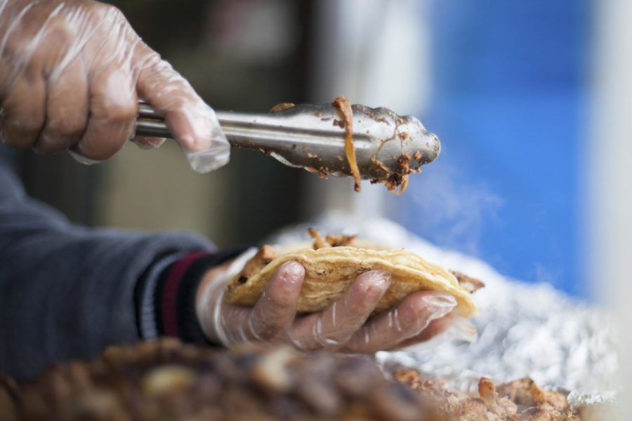 Pedro Cuobo scoops chicken into two corn tortillas. (Photo by Christian Snyder | Multimedia Editor)
