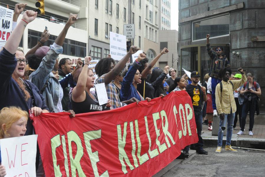 Protestors at a June protest raise their fists, chant and lead the crowd with a banner that reads, Fire Killer Cops.” The banner referenced the death of 17-year-old Antwon Rose, after he was fatally shot by East Pittsburgh police officer Michael Rosfeld on June 19. (Photo by Anne Amundson | Staff Photographer)
