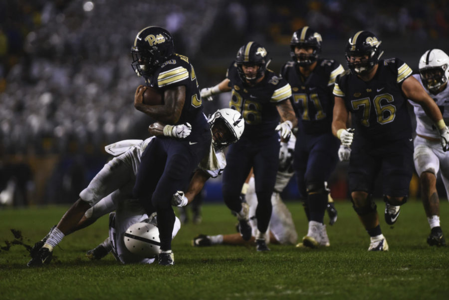 Running back Quadree Ollison (30) gets tackled in a muddy game against Penn State. 