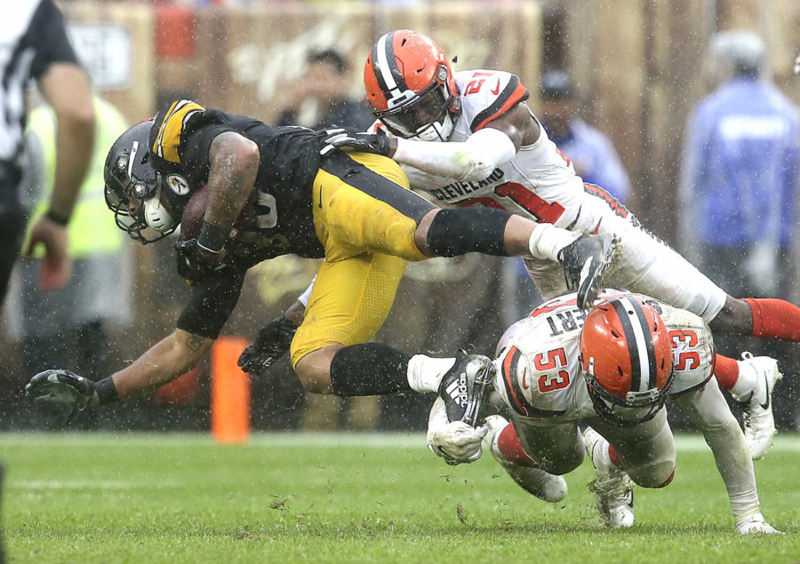 Cleveland Browns Denzel Ward (top) and Joe Schobert take down Pittsburgh Steelers James Conner during overtime Sunday at FirstEnergy Stadium in Cleveland. The game ended in a 21-21 tie.