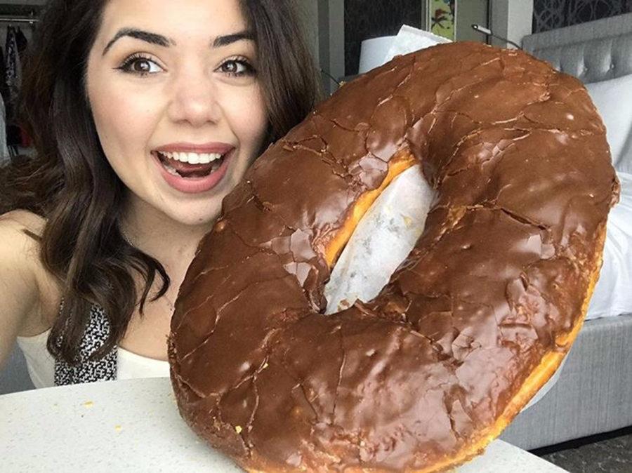 Elaine Khodzhayan poses for a selfie with a giant chocolate-frosted doughnut.