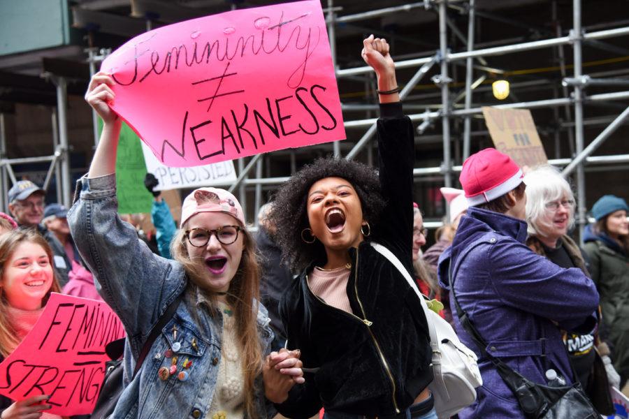 Two marchers cheer while passing through downtown Pittsburgh during the 2018 Women’s March.
