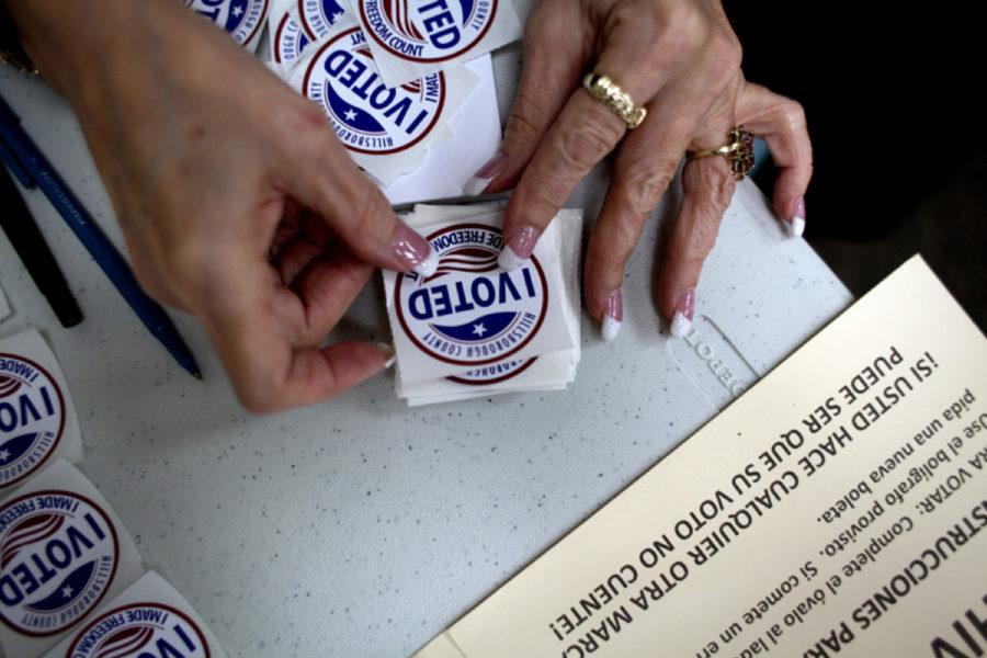 A poll worker gets “I Voted” stickers ready to hand to voters as they finish up at the ballot booths. 