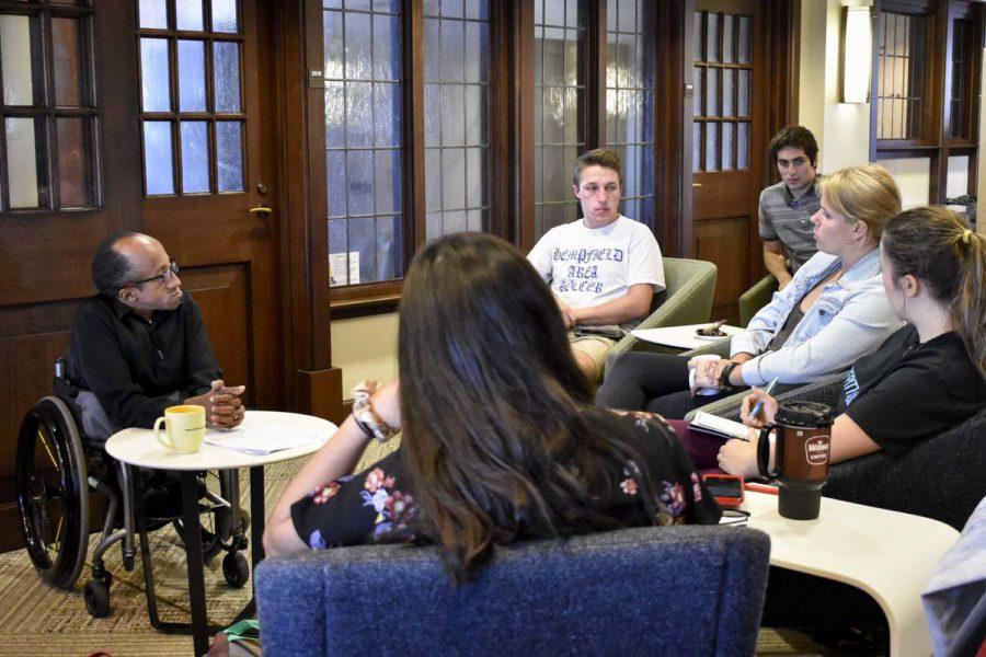 Chaz Kellem (far left), director of Pitt Serves, speaks with students at Thursday afternoon’s Community Cafe event in the Cathedral of Learning.

