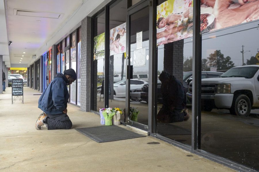 Acworth resident Derrick Franklin places flowers near the entrance of Youngs Asian Massage Parlor Wednesday, March 17, 2021 in Cherokee County, Georgia.