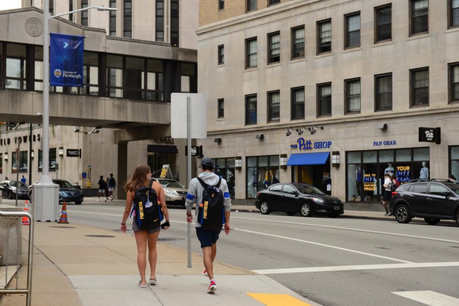 Two+students+walk+along+the+sidewalk+adjacent+to+David+Lawrence+Hall.