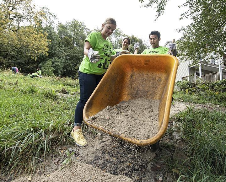 Pitt undergraduates Arabella Johnson and Brianna Raskin (left) and graduate student Jinghang Li (right) help with gardening at Duncan Park in Lawrenceville on Saturday.