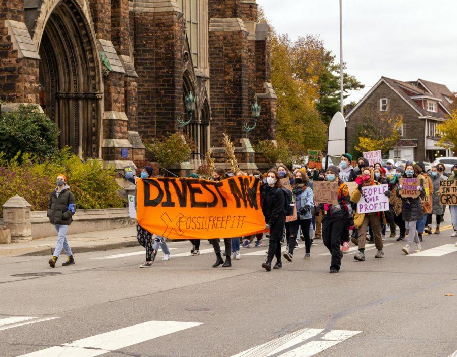 Pitt, Chatham and Carnegie Mellon students walk down the street with a banner that reads “Divest Now” during Saturday’s “College Climate March.”
