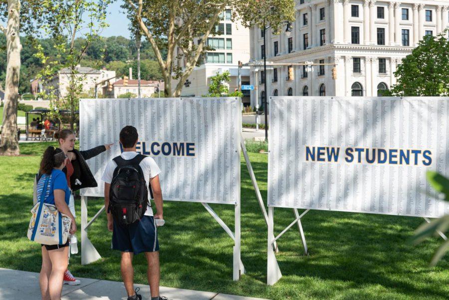 Three students read a sign greeting Pitt’s largest incoming class ever this year — a total of 5,195 students. 
