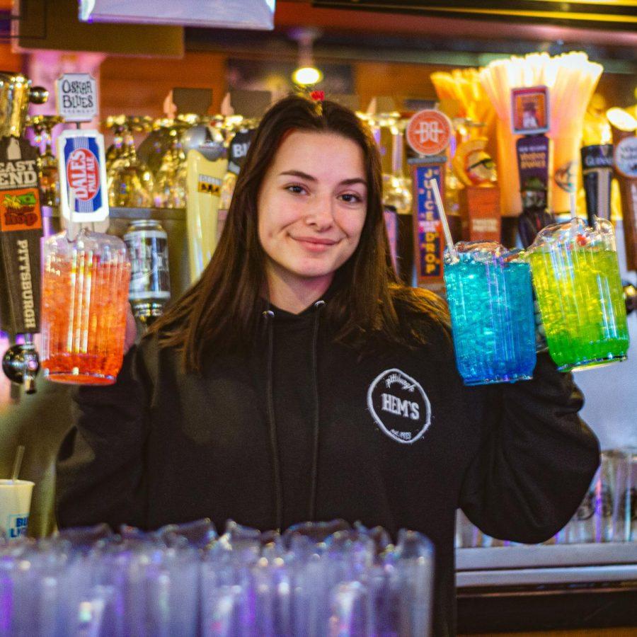 A bartender holds up drinks at Hemingways Cafe.