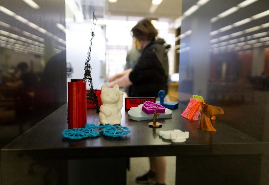 A Pitt student works in Hillman’s Open Lab Room behind 3D printed objects.