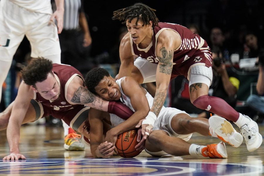 University of Miami redshirt senior guard Charlie Moore (3), center, Boston College first-year guard Jaeden Zackery (3), left, and Boston College graduate student guard Makai Ashton-Langford (11), right, battle for the ball during quarterfinals of the Atlantic Coast Conference tournament on Thursday in New York. 