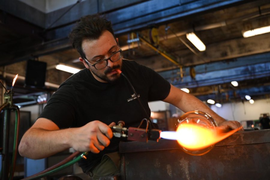 Zach Layhew, a Pittsburgh Glass Center artist-in-residence, works on the shape of a glass bottle.