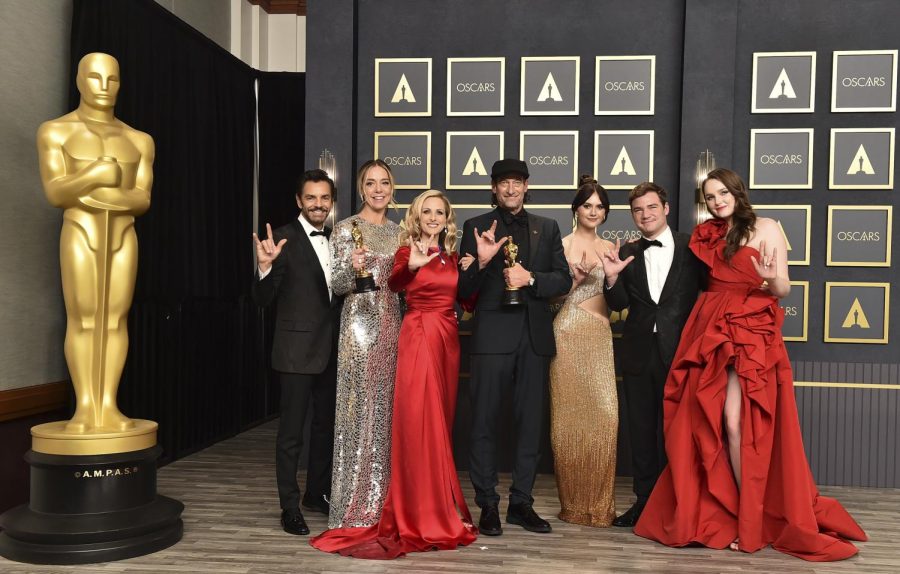 Eugenio Derbez, from left, Sian Heder, Marlee Matlin, Troy Kotsur, Emilia Jones, Daniel Durant, and Amy Forsyth, winners of the award for best picture for CODA, pose in the press room while signing I love you at the Oscars on Sunday, March 27, 2022, at the Dolby Theatre in Los Angeles.