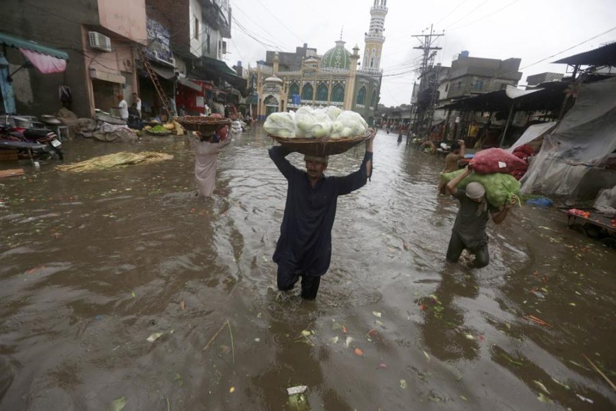 Laborers carry produce as they wade through a flooded road after heavy rainfall in Lahore, Pakistan, in July. 
