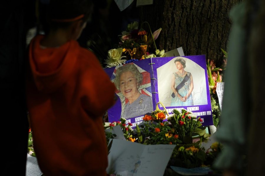 Flowers and pictures brought for the recently deceased Queen Elizabeth II of England rest near a picture of her at Green Park in London, England on Sunday.
