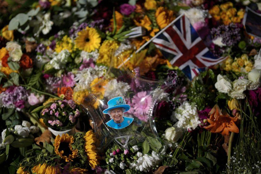 A balloon with a picture of Queen Elizabeth II and a British flag placed between flowers for the Queen at Green Park, near Buckingham Palace in London on Monday, Sept. 12, 2022.