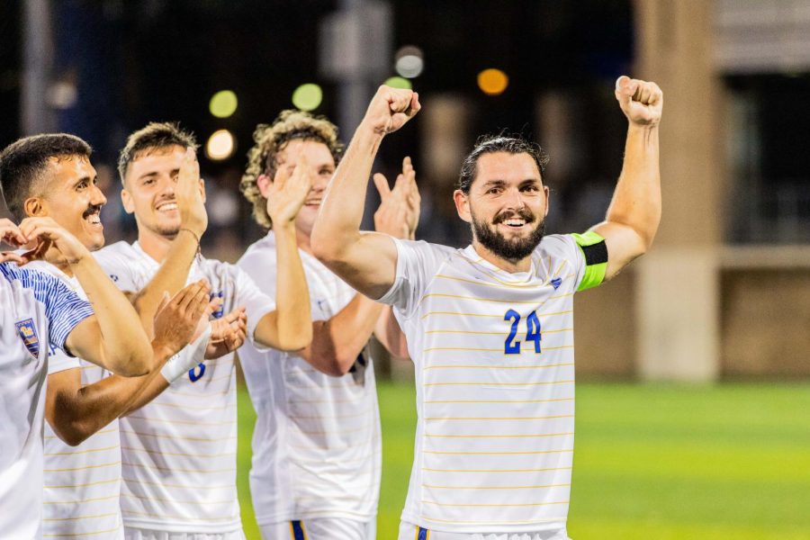 Graduate student Jackson Walti (24) celebrates with Pitt men's soccer team after winning a game vs. West Virginia in August. 
