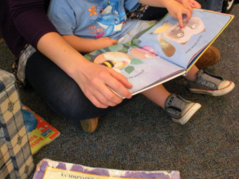 An educator reads to a child enrolled in the UCDC child care program. 
