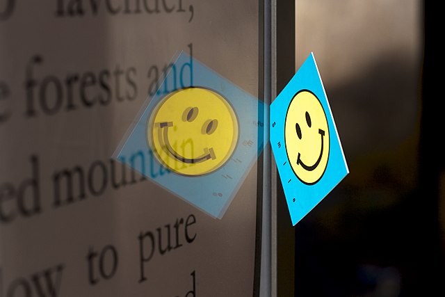 A card with a smiley face is reflected in a display.