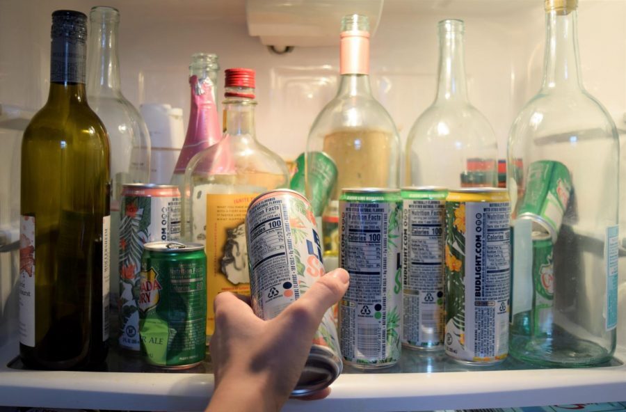 A student places a can of alcoholic seltzer into a fridge.
