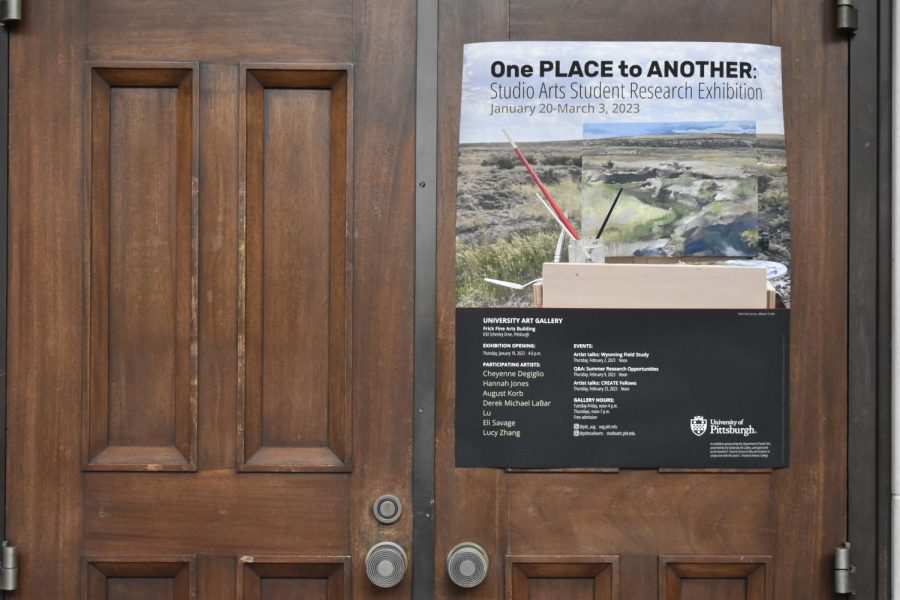 A sign advertising the “One Place to Another” exhibit in the Frick Fine Arts building.
