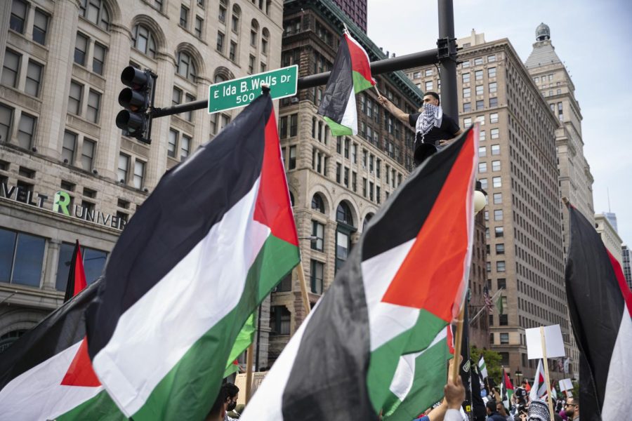 A+supporter+holds+up+a+flag+while+atop+a+stoplight+as+protesters+walk+below+during+a+rally+and+march+in+support+of+Palestinians+in+Chicago+in+response+to+an+ongoing+assault+between+Israelis+and+Palestinians+in+the+Middle+East+on+Sunday%2C+May+16%2C+2021.+
