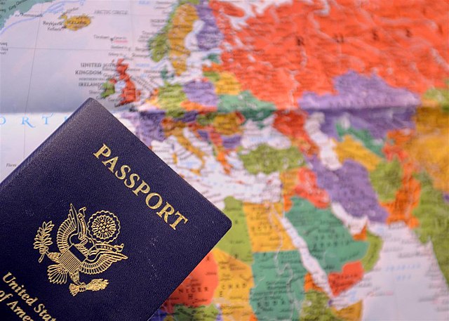 A United States passport in front of a world map.