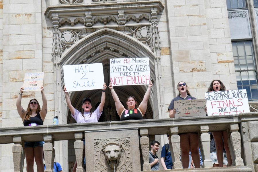 Protestors chant and hold signs in front of the Cathedral of Learning Friday afternoon.