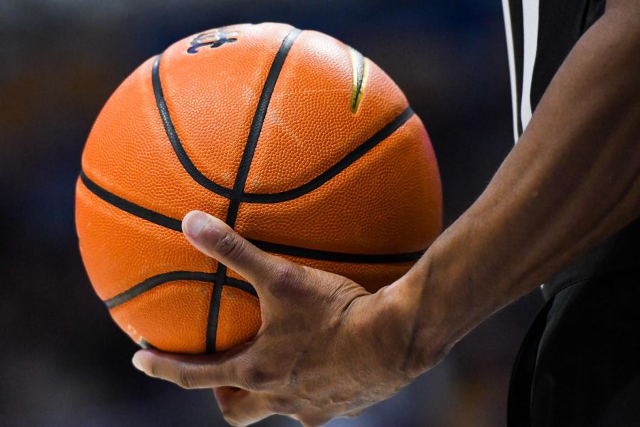 A referee holds a basketball in the Petersen Events Center.