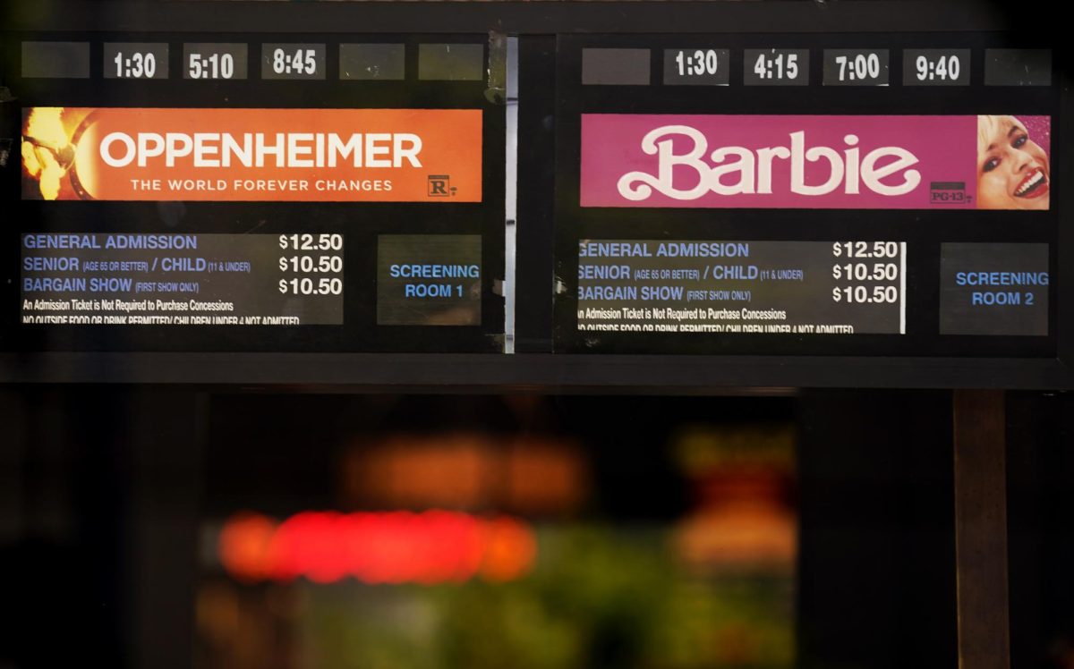 Showtimes for the films Oppenheimer and Barbie are pictured behind the box office window at the Los Feliz Theatre on Friday, July 28 in Los Angeles. 