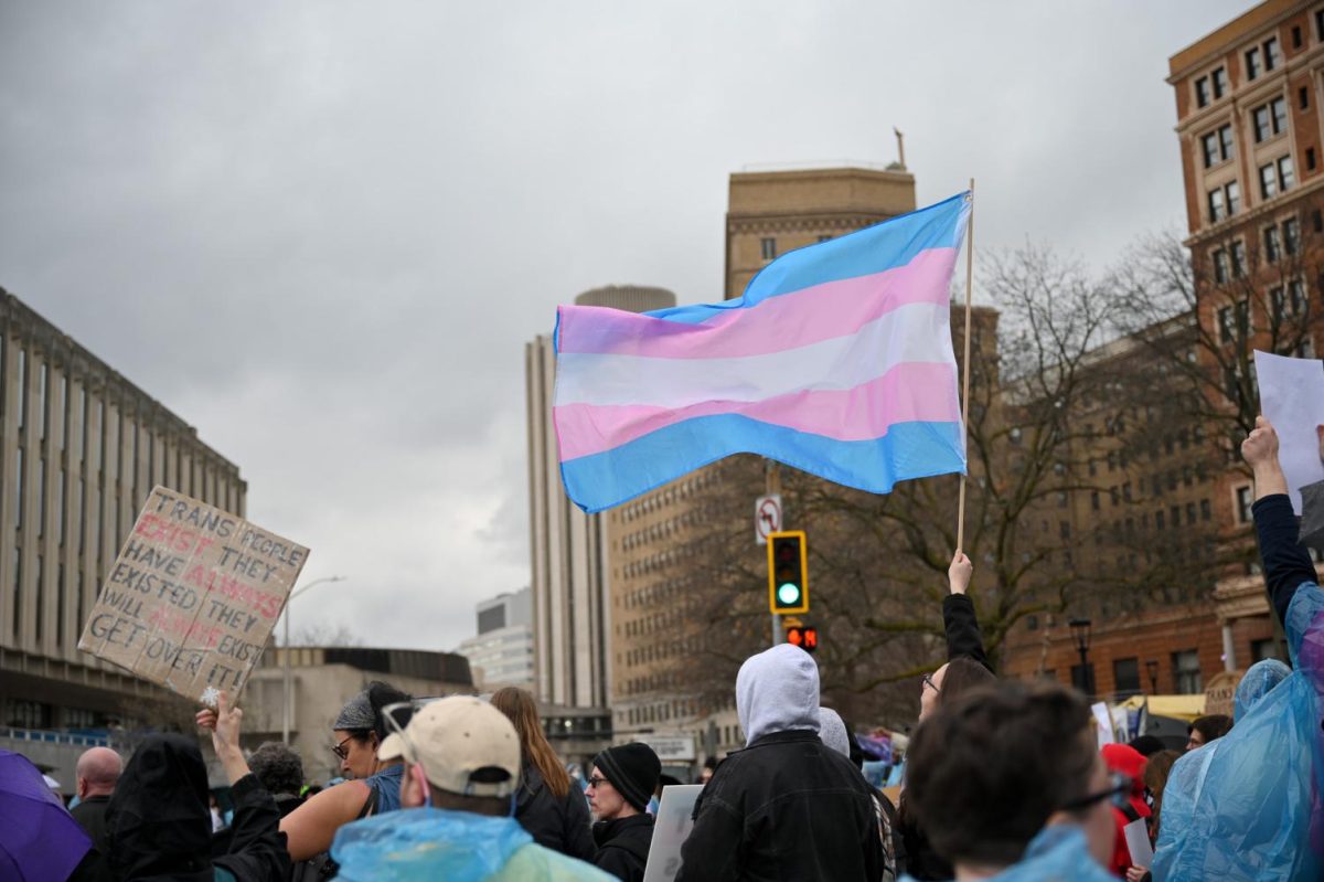 A protester holds up a transgender pride flag at a rally protesting Riley Gaines’ appearance at the O’Hara Ballroom on March 27, 2023.