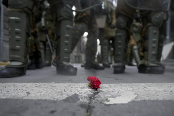 Police stand in front of a flower set on the street during a demonstration marking the 50th anniversary of a military coup led by Gen. Augusto Pinochet outside La Moneda presidential palace in Santiago, Chile on Sunday, Sept 10, 2023. 