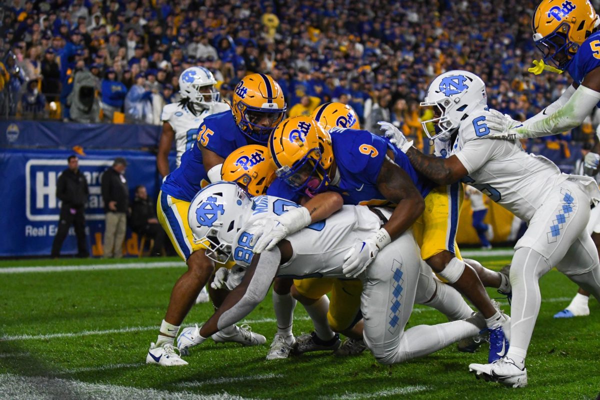 Players tackle each other to the ground during Saturday night's game against UNC at Acrisure Stadium.