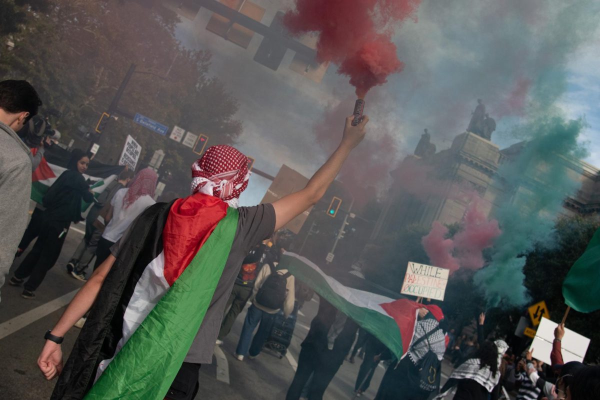 A man waves colored smoke in a rally in support of Palestine in Oakland Friday afternoon. 