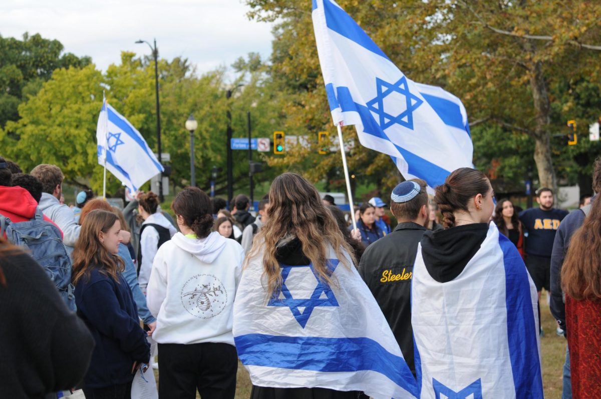 Israel Peace Rally participants gather in a circle draped in Israeli flags to sing prayers in Schenley Plaza on Monday evening. 