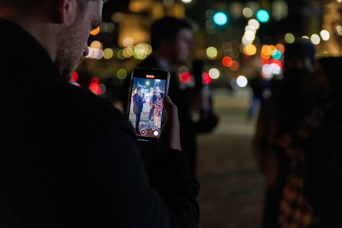 A passerby films an interaction between James O’Keefe and a protester before his event outside of the O’Hara Student Center on Thursday night. 