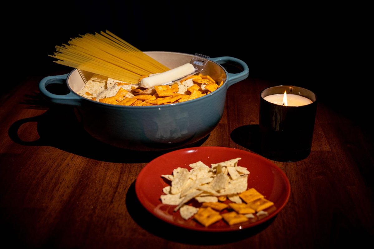A candlelit meal consisting of Cheez-Its, Tostitos, dry spaghetti, and a wrapped string cheese.