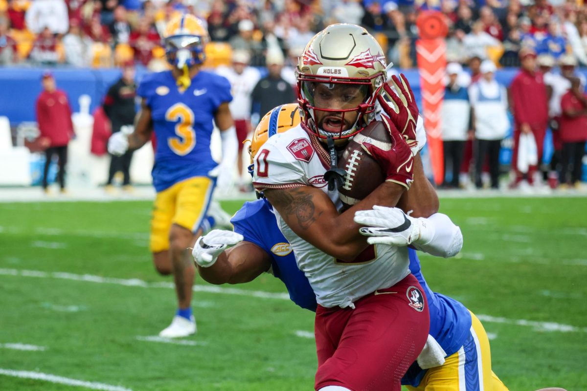 FSU redshirt junior wide receiver Ja’Khi Douglas (0) protects the football while being tackled by a Pitt player during Saturday afternoons game at Acrisure Stadium.