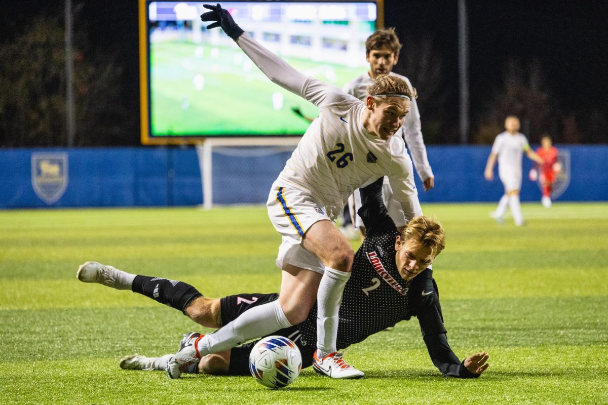 Junior midfielder Michael Sullivan (26) is tackled by an opposing player during the ACC Championship tournament first round match against Louisville on Wednesday night at the Petersen Sports Complex.